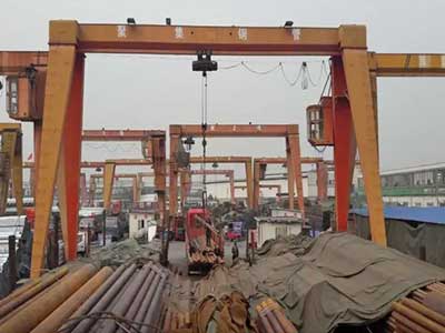 Gantry crane with hook and chain slings for steel pipe handling